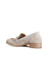 Beige suède instappers met een lage houten hak, voorzien van een decoratieve band en details in goud, een gladde textuur en gestikte accenten.