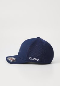 Tumesinine pesapalli kork, millel on võrgust tagaosa, kaarene visor ja tõmblusega "T.T. PRO" külgedel. Eesmisel paneelil on logo.