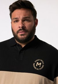 Černé a béžové polo triko s límcem, které má na oblasti hrudníku kulaté logo. Tkanina vypadá hladce a má pohodlný střih.