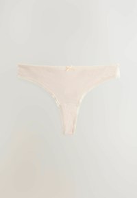 Beige trosa med spetstjejer och en liten rosett detalj fram. Tillverkad av mjukt tyg, med en minimal design och slät textur.