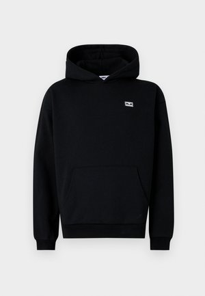 Black hooded sweatshirt made of soft fabric. Features a front pocket, ribbed cuffs, and a small branded patch on the chest.