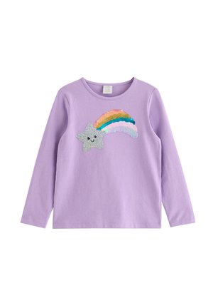 Ung pige i lilla outfit, der går og bærer en mørkeblå snor-rygsæk med kanin- og stjernemønstre.