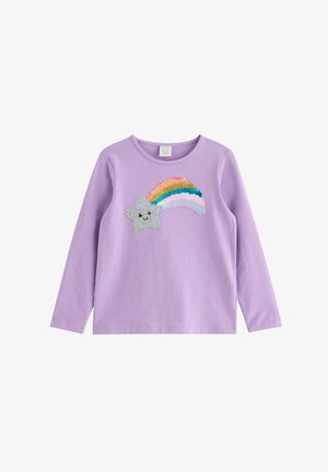 Ung pige i lilla outfit, der går og bærer en mørkeblå snor-rygsæk med kanin- og stjernemønstre.
