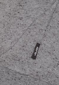 Grijze stof met een gestructureerd patroon, met een zwart label met de tekst "J&JOY." Zachte textuur met een diagonale plooi zichtbaar.