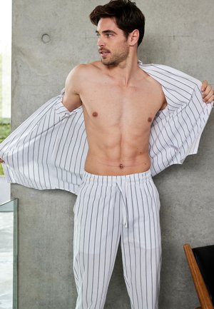 Hvidstribet pyjamas sæt med en skjorte med knapper og bukser med elastisk talje. Stoffet ser let, glat og åndbart ud.