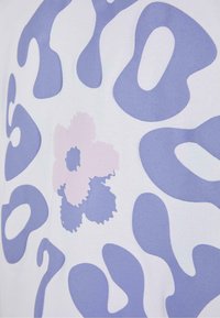 Bomull T-skjorte med hvit bakgrunn, store lilla abstrakte former og detaljer i pastellrosa blomster, glatt tekstur og moderne design.