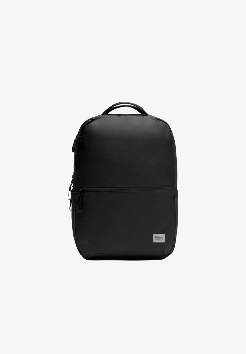 Mustassa reppussa on kestävä kangas, suorakulmainen muoto, vetoketjukiinnitys, ylhäällä oleva kahva, etutasku ja logopatch.