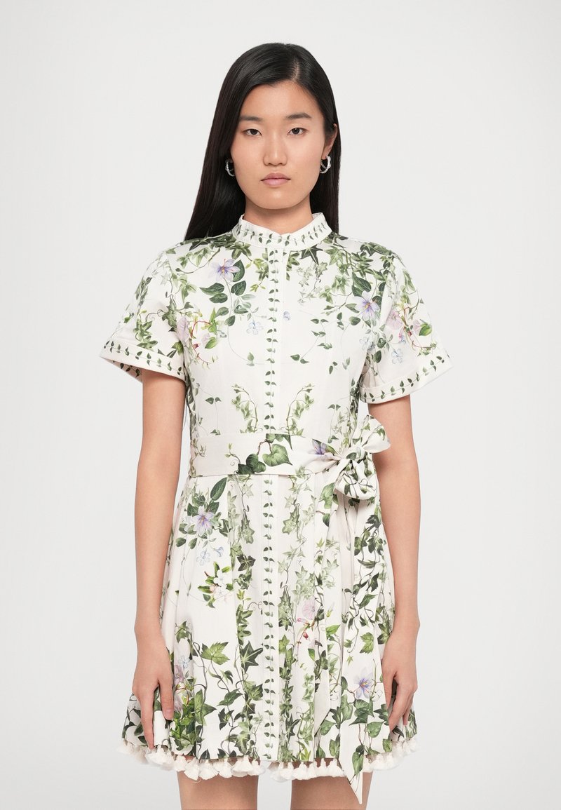 Bloemendrukjurk van witte stof met korte mouwen, hoge hals, getailleerde taille, zijstrikdetail en kantafwerking aan de zoom.