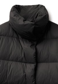 Černá prošívaná bunda s vysokým límcem, s hladkým, lesklým povrchem a prošívanými částmi pro izolaci. Minimalistický design, žádné viditelné kovové prvky.