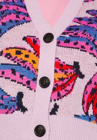 Strikket cardigan med v-udskæring, pastelpink baggrund og farverige bananmønstre. Den har sorte knapper og ribbet tekstur langs kanterne.