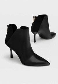 Czarne botki za kostkę z gładkiej skóry, o spiczastych noskach, szpilkach oraz zamkach błyskawicznych z tyłu; elegancki i nowoczesny design.