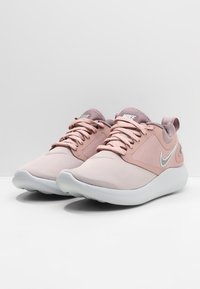 Sneaker Nike in rosa chiaro e grigio, con una tomaia testurizzata, punta rotonda, lacci frontali e colletto imbottito per il comfort.