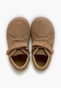 Zapatos de ante marrón con punta redondeada, cordones elásticos y una correa de Velcro. El interior es suave y acolchado para mayor comodidad.