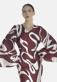 Abito in satin rosso con motivi ondulati bianchi, maniche a campana lunghe e scollatura rotonda profonda. Tessuto liscio con silhouette aderente.