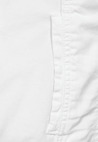 Tessuto bianco con una texture liscia e una leggera lucentezza, con una tasca laterale e cuciture a contrasto lungo i bordi.