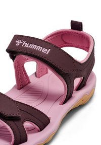 Brauner und rosa Kindersandale mit verstellbaren Riemen und gepolsterter Sohle. Verfügt über eine strukturierte rosa Innensohle und eine flexible Gummiaußensohle.