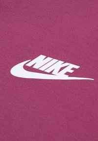 Un tissu bordeaux au toucher lisse présente un logo Nike blanc en caractère stylisé, situé au centre.