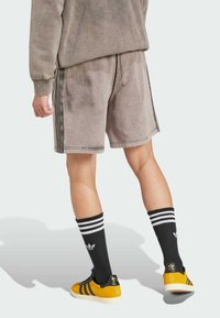 Gray shorts with black side stripes, paired with black and white striped socks and yellow athletic shoes. Soft material and relaxed fit.