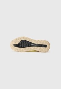 Soletta leggera per scarpe con una superficie in gomma nera texturizzata e una suola esterna beige, dotata di un motivo a battistrada per grip e trazione.