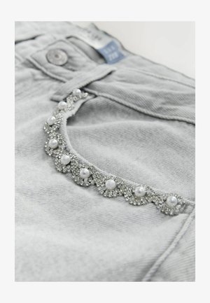 Gray denim jeans featuring a decorative trim with clear and white pearl-like embellishments, enhancing the pockets with a textured appearance.