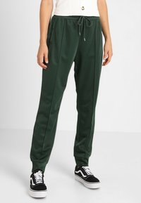 Gröna polyesterjoggers med avslappnad passform, dragsko i midjan, sidofickor, tapered mudd och subtila veck fram.