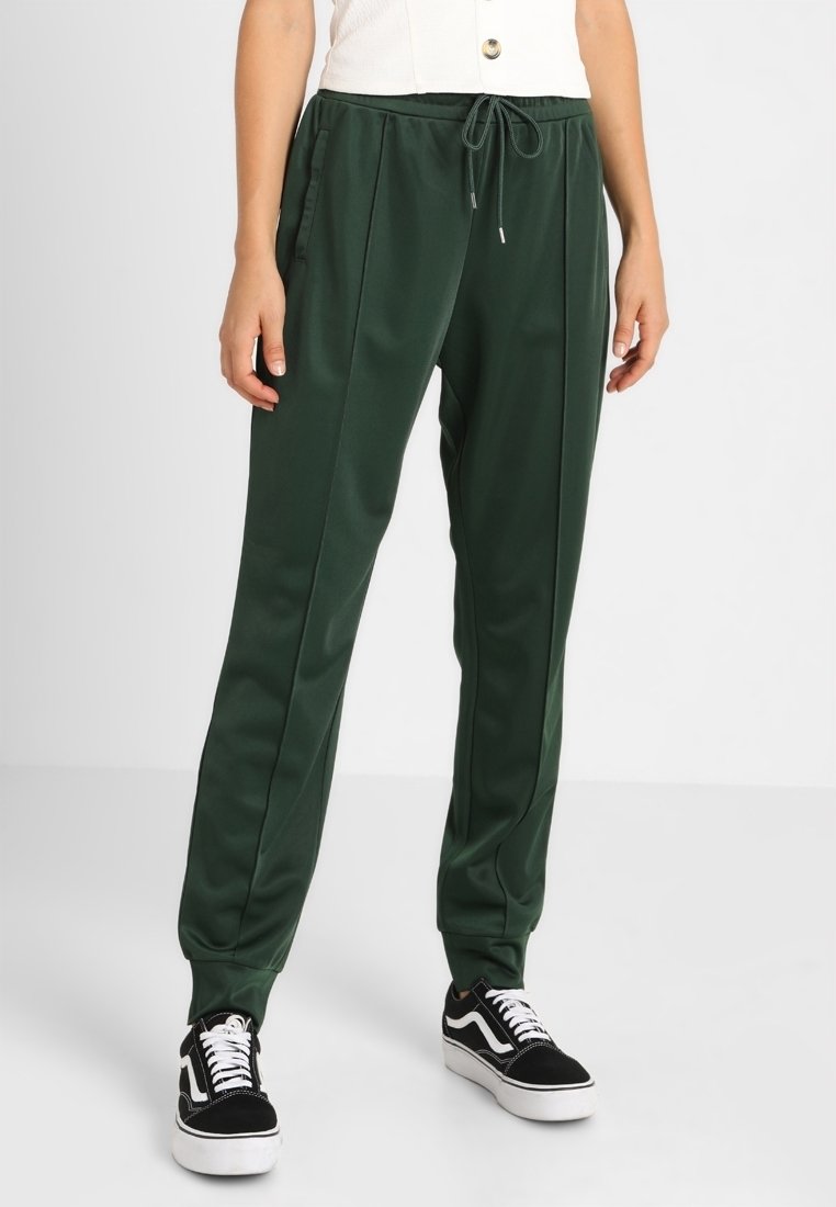 Gröna polyesterjoggers med avslappnad passform, dragsko i midjan, sidofickor, tapered mudd och subtila veck fram.