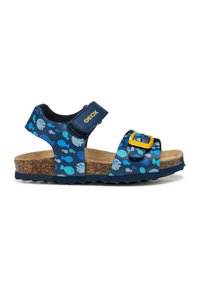 Sandali blu con motivo a pesci, cinturino regolabile, fibbia gialla, outsole in sughero e suola testurizzata, progettati per comfort e traspirabilità.