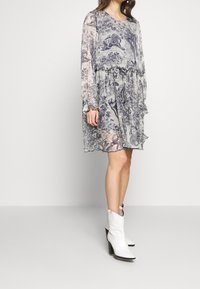 Šaty s květinovým vzorem, dlouhý rukáv, v šedých a modrých odstínech. Mají volánový lem a rukávy, volný střih a lehký, průhledný materiál.