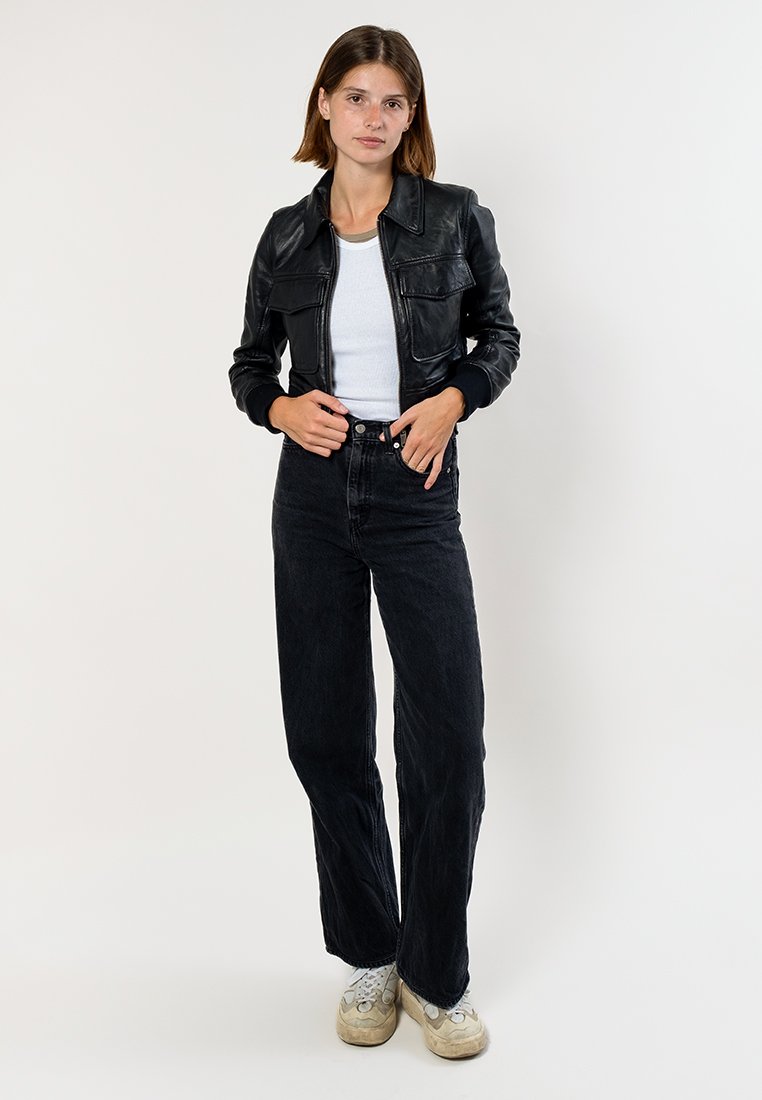 Zwarte leren jas met voorzakken, witte T-shirt, hoog-waist zwarte jeans en witte sneakers. Eenvoudig ontwerp, gladde textuur.