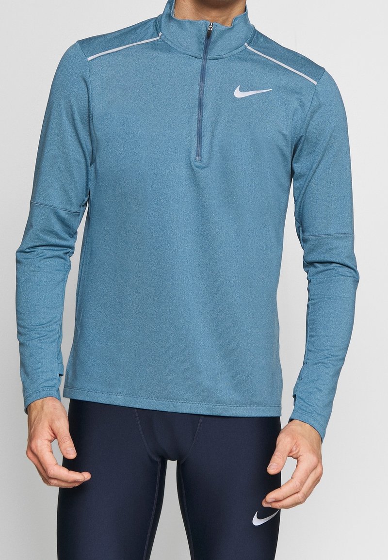 Maglia atletica blu a maniche lunghe con collo a mezza zip, accenti bianchi, tessuto elasticizzato e design aderente, adatta per sport o esercizio.