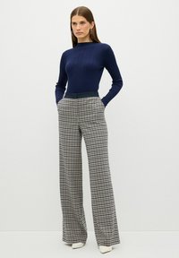 Námořnický žebrovaný dlouhý rukáv spárovaný s širokými kostkovanými kalhotami v černé a bílé barvě, s přiléhavým pasem a bočními kapsami.