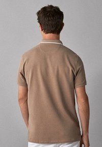 Khaki koszulka polo z krótkim rękawem i białym wykończeniem kołnierza, charakteryzująca się gładką teksturą i dopasowanym fasonem, pokazana z tyłu.