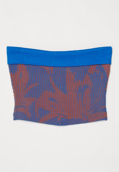 Ελαστικό τοπ σωλήνα με μια μπλε συμπαγή ταινία στην κορυφή. Το κύριο σώμα διαθέτει υφή με πατίνα από κόκκινες και μπλε κατακόρυφες ρίγες.