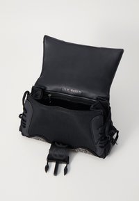 Sac à main noir en cuir lisse et tissu texturé. Dispose d'une poche zippée et de lacets décoratifs. Fermeture à boucle sécurisée.