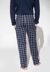 Granatowe spodnie piżamowe w białą kratę, z elastycznym paskiem w talii, bocznymi kieszeniami i luźnym krojem. Miękki materiał o gładkiej fakturze.