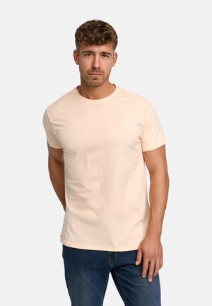 Tricou din bumbac de culoare piersiciu deschis, cu guler rotund și mâneci scurte. Prezintă un mic logo pe partea superioară stângă a pieptului. Textură moale.