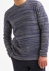 Tummansininen pitkähihaisena paita, jossa on harmaat vaakasuorat raidat, pyöreä kaula-aukko ja teksturoitu kangas. Ominaisuuksina istuva siluetti ja hienovarainen kuosi.