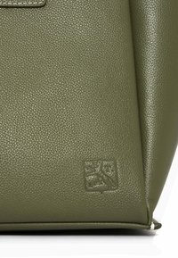 Sac à main en cuir texturé vert avec un logo carré et un design structuré. Remarquable pour sa finition lisse et sa forme angulaire.