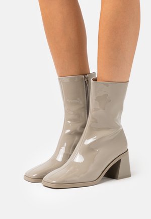 Beżowe lakierowane botki za kostkę ze square toe i słupkowym obcasem, z bocznym zamkiem błyskawicznym i gładką, błyszczącą teksturą.