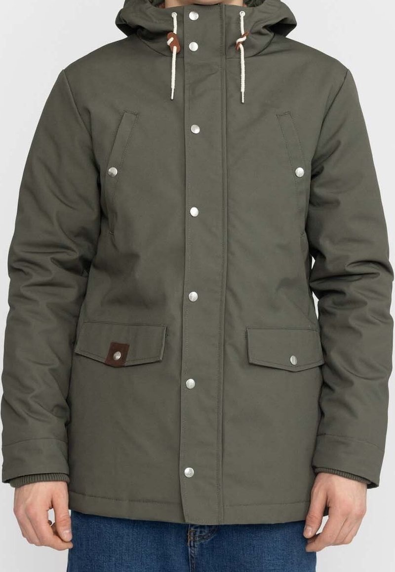 Olivgrön isolerad jacka med huva, knappknäppning fram, två bröstfickor och elastiska ärmslut; har kontrasterande bruna läderdetaljer.