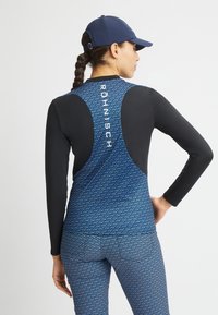 Top atletico a maniche lunghe di colore blu con dettagli neri, caratterizzato da un motivo geometrico e un logo sul retro. Tessuto elastico e testurizzato.