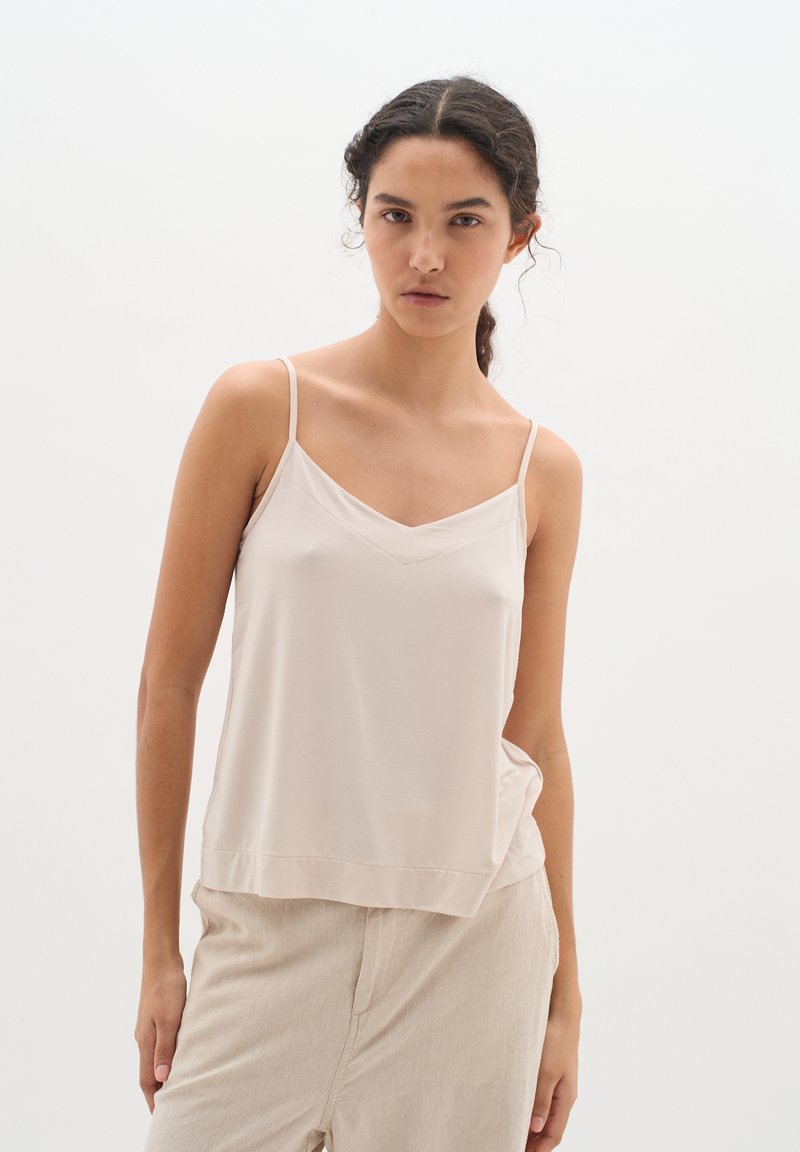 Top in cammello chiaro con spalline sottili, scollatura a V, un fit morbido e tessuto morbido, abbinato a pantaloni beige chiaro per un look coordinato.