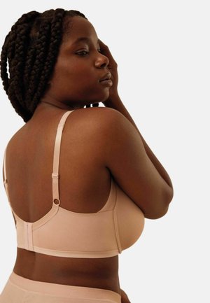 Sujetador nude con tirantes ajustables, copas sin costuras y textura suave. Cuenta con cierre de gancho en la parte trasera y diseño minimalista.