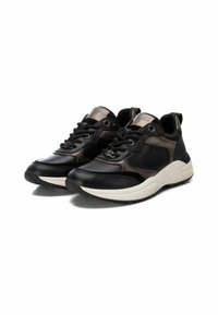 Zapatillas deportivas negras y marrones con una mezcla de cuero y materiales sintéticos, que cuentan con una superficie texturizada y una media suela blanca.