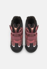 Red and black winter boots with adjustable straps, fur-lined interior, textured surfaces, and a rubber sole. Rounded toe design.