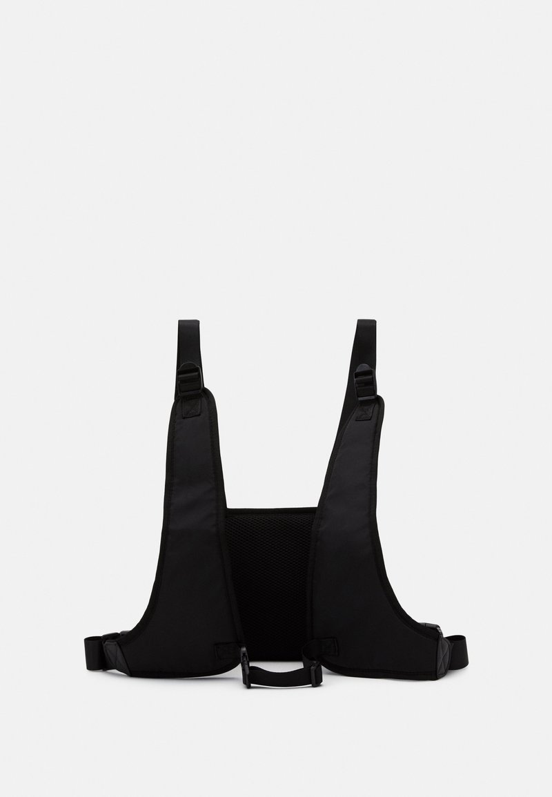 Gilet harnais noir réglable avec panneau arrière en maille et fermetures à boucle, conçu pour un ajustement sécurisé et un confort optimal.