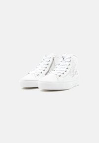 Ζευγάρι λευκά ψηλά αθλητικά παπούτσια με κορδόνια, πλαϊνό φερμουάρ και λεπτομέρειες με δίχτυ σε απλό λευκό φόντο.