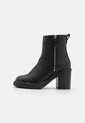 Bottines en cuir noir avec une finition texturée, dotées d'une fermeture éclair sur le côté, d'un bout rond et d'un talon épais.