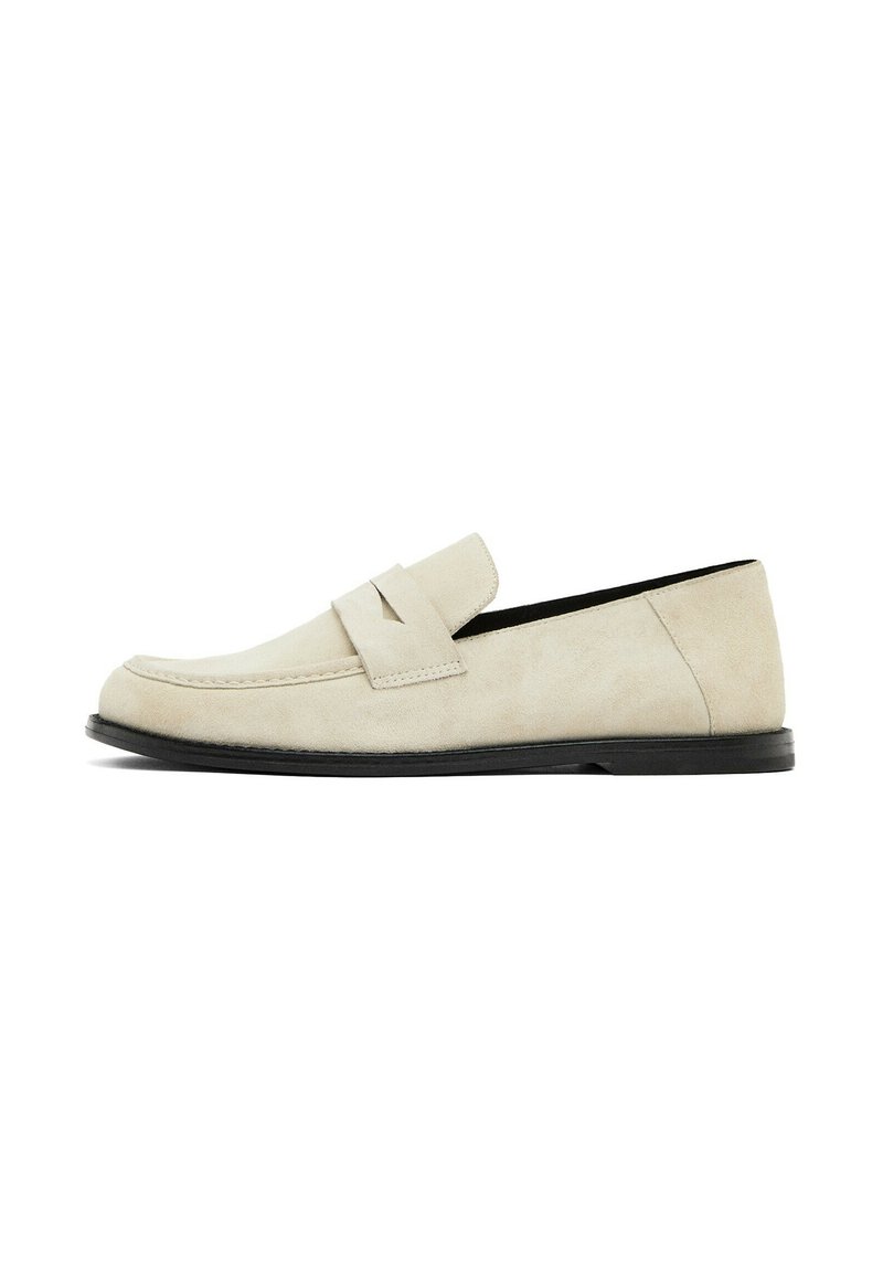 Beige suede loafers with a rounded toe, decorative strap accent across the vamp, and a slim black sole, showcasing a smooth texture.