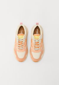 Sneakers har en kombinasjon av fersken- og kremfargede materialer med mesh-detaljer, rund tå, snøring, og en rosa hæltab.
